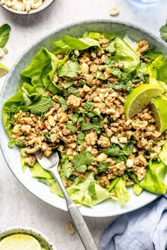 a bowl filled with lettuce, meat and cilantro on top of a table