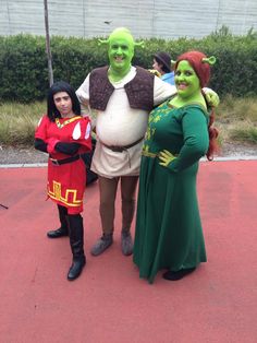 three people dressed up in costumes standing next to each other on a red carpeted area