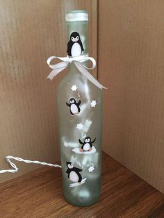 a bottle with penguins painted on it sitting on top of a wooden table next to a wall