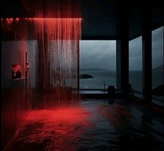 a red shower head in the middle of a room with water flowing from it's walls