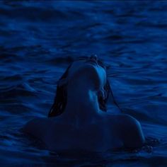 a woman floating in the water at night with her head above the water's surface