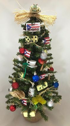 a small christmas tree decorated with ornaments and letters on the top, in front of a white background