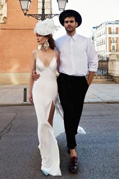 a man and woman are walking down the street in formal wear with hats on their heads