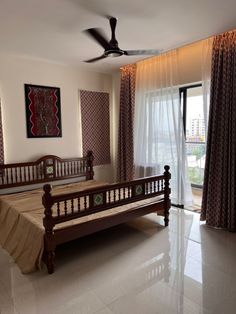 a bed room with a neatly made bed next to a window and a ceiling fan