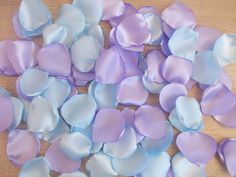 purple and blue petals are scattered on a wooden surface, as if they were made out of satin material