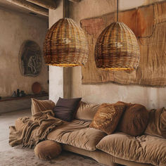 two lamps hanging from the ceiling above a couch in a room with pillows on it