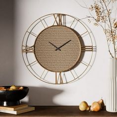 a clock that is on the side of a wall next to a vase with flowers