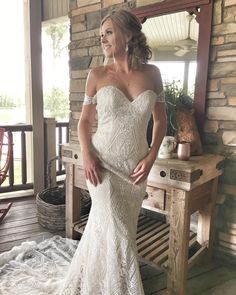 a woman in a white wedding dress standing on a porch with her hands on her hips