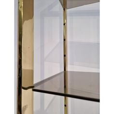 an empty shelf with glass shelves on each side and metal bars at the bottom, in front of a white wall