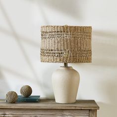 a white vase sitting on top of a wooden table next to a lamp and books