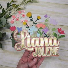 a person holding up a card with flowers and the word ligona joliee on it