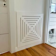 a bathroom with white walls and wood flooring next to a toilet paper dispenser