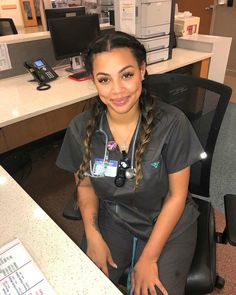 a woman in scrubs sitting at a desk