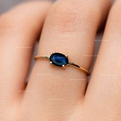 a woman's hand with a gold ring and blue stone on the middle finger