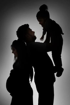 a man holding a baby while standing next to a woman