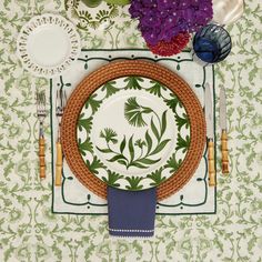 a place setting with plates, silverware and purple flowers on the tablecloths