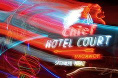 blurry photograph of neon lights in front of a hotel court sign that reads,