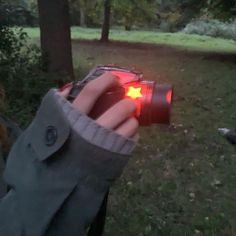 a person holding up a camera in the woods with their hand on it's lens