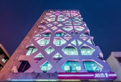 a tall building lit up at night with neon lights on it's sides and windows