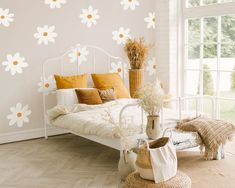 a white bed sitting next to a window in a room with flowers on the wall