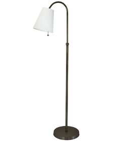 a floor lamp with a white shade on the base and a black metal pole in front of it