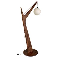 a lamp that is on top of a wooden stand with a white ball hanging from it