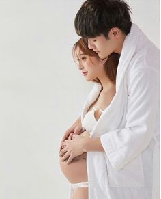 a pregnant woman in a bathrobe standing next to a man wearing a robe