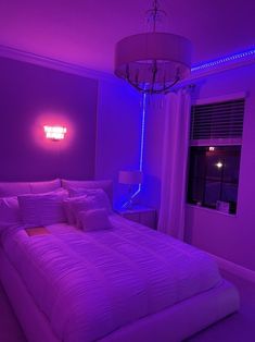 a bed in a room with purple lights on the walls and a chandelier