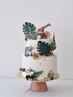 a three tiered cake decorated with jungle animals and leaves