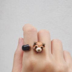 a person's hand with a ring made to look like a fox