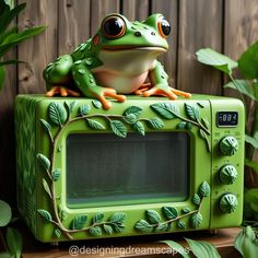 a frog sitting on top of a green microwave oven with leaves painted on the front