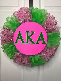 a pink and green wreath with the letters aka on it's front door