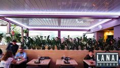 people sitting at tables in a restaurant with plants growing on the wall and ceiling above them