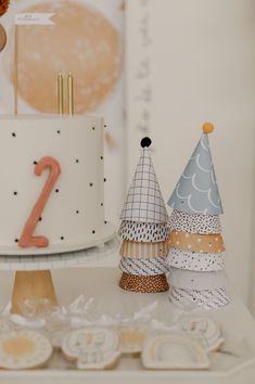 two decorated birthday cakes sitting on top of a white table next to cupcakes