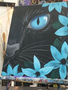 a painting of a black cat with blue eyes surrounded by flowers