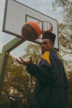 a young man standing in front of a basketball hoop with his hands out to catch the ball