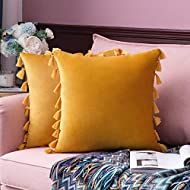 two yellow pillows sitting on top of a pink couch next to a vase with flowers