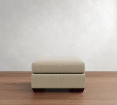 a footstool sitting on top of a wooden floor next to a white wall