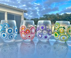 four wine glasses with designs on them sitting in front of a building and blue sky