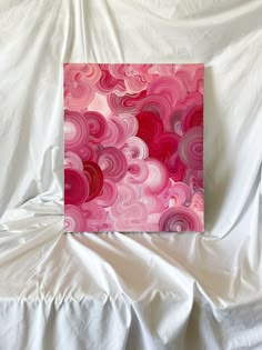 a pink and red painting sitting on top of a white sheet