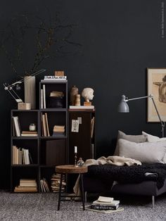 a living room filled with furniture and bookshelves next to a wall mounted lamp