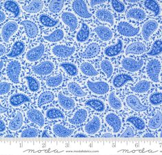 a blue and white paisley print fabric with a ruler in front of the image, it is