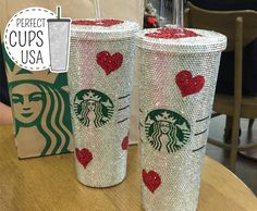 two starbucks cups with hearts on them sitting on a table