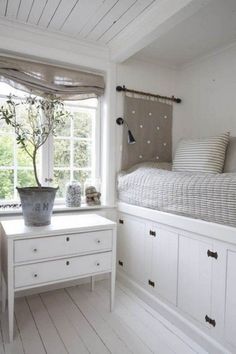 a bedroom with white walls and flooring has a bed, dresser, window, and potted plant in the corner