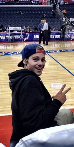 a man sitting on top of a basketball court with his hand up in the air