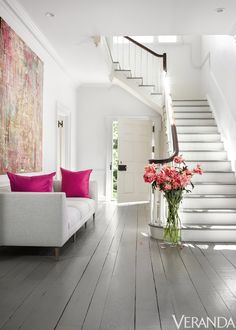 a living room filled with furniture and flowers on the floor next to a stair case