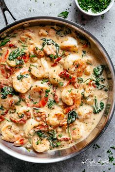 a pan filled with shrimp and spinach on top of a gray counter next to two bowls