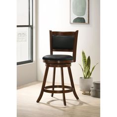 a wooden bar stool with a black padded seat and back rests in front of a window next to a potted plant