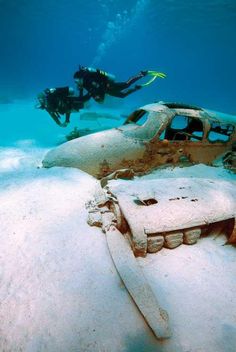 a scuba diver swims next to an abandoned car in the ocean