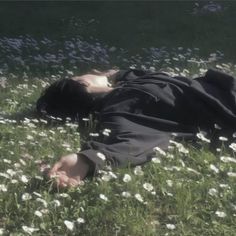 a man laying in the grass with his head on his back and eyes closed,